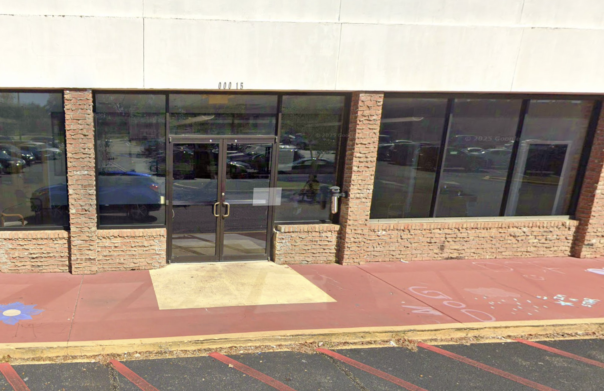 Glass double-door entrance with brick facade and large windows