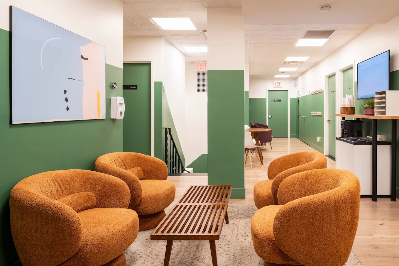 Lounge with curved chairs, coffee table, and green accents