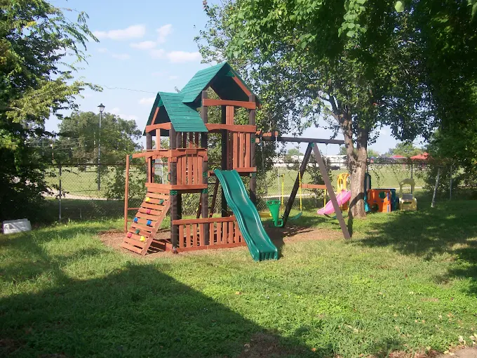 Outdoor playground with slide and climbing structure near trees