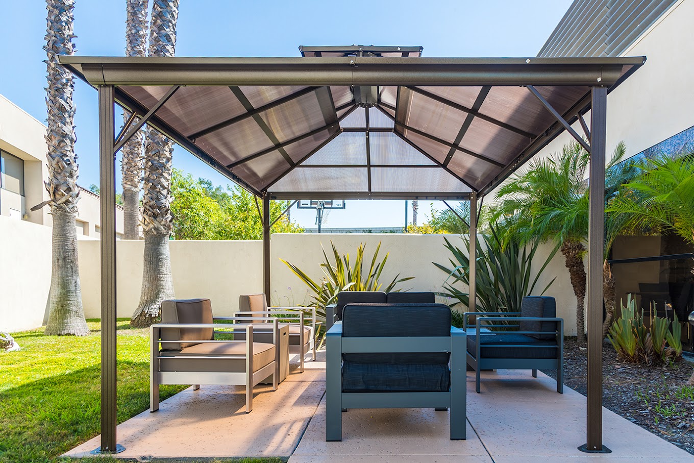 A shaded outdoor seating area with cushioned chairs and tropical plants