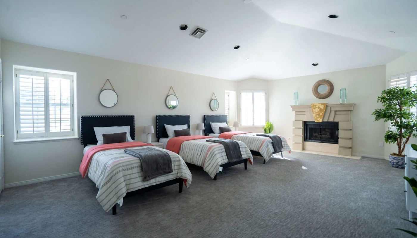 Room with 3 beds and a decorative fireplace