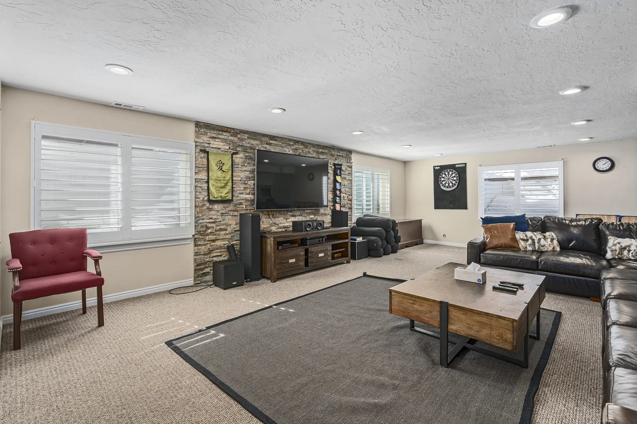 Lounge with TV, dartboard, and black leather couch