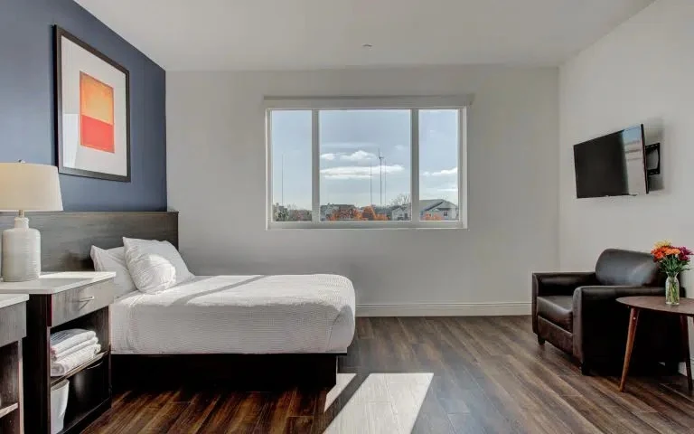 Bright room with white bed, armchair, and TV