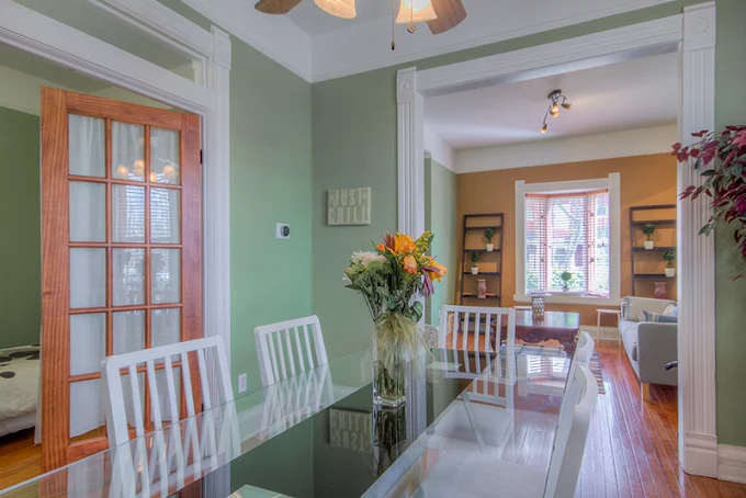 Dining space with glass table, white chairs, and floral decor