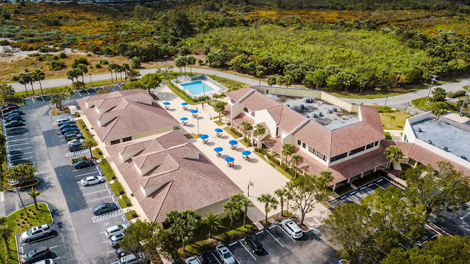 An aerial view of a large, inviting facility with spacious courtyards, a pool, and surrounding greenery, offering a tranquil and welcoming atmosphere.