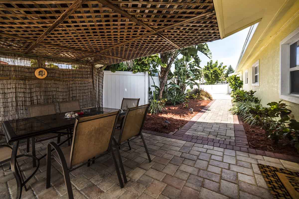 Outdoor seating under wood lattice with tropical landscaping