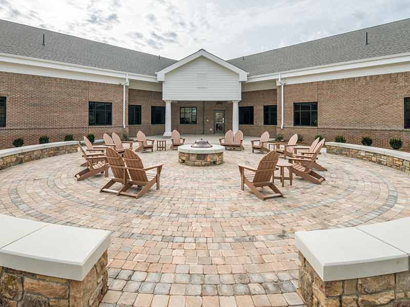 Outdoor courtyard with Adirondack chairs around a fire pit
