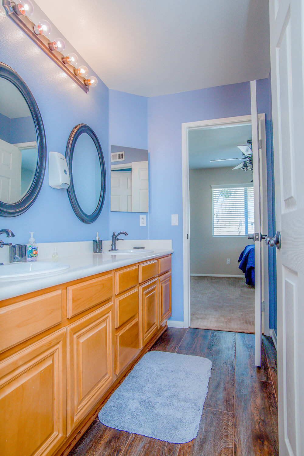 Double-sink bathroom with wood cabinets and two mirrors