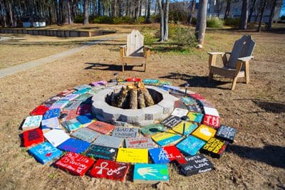 Firepit ringed with painted tiles and two wooden chairs