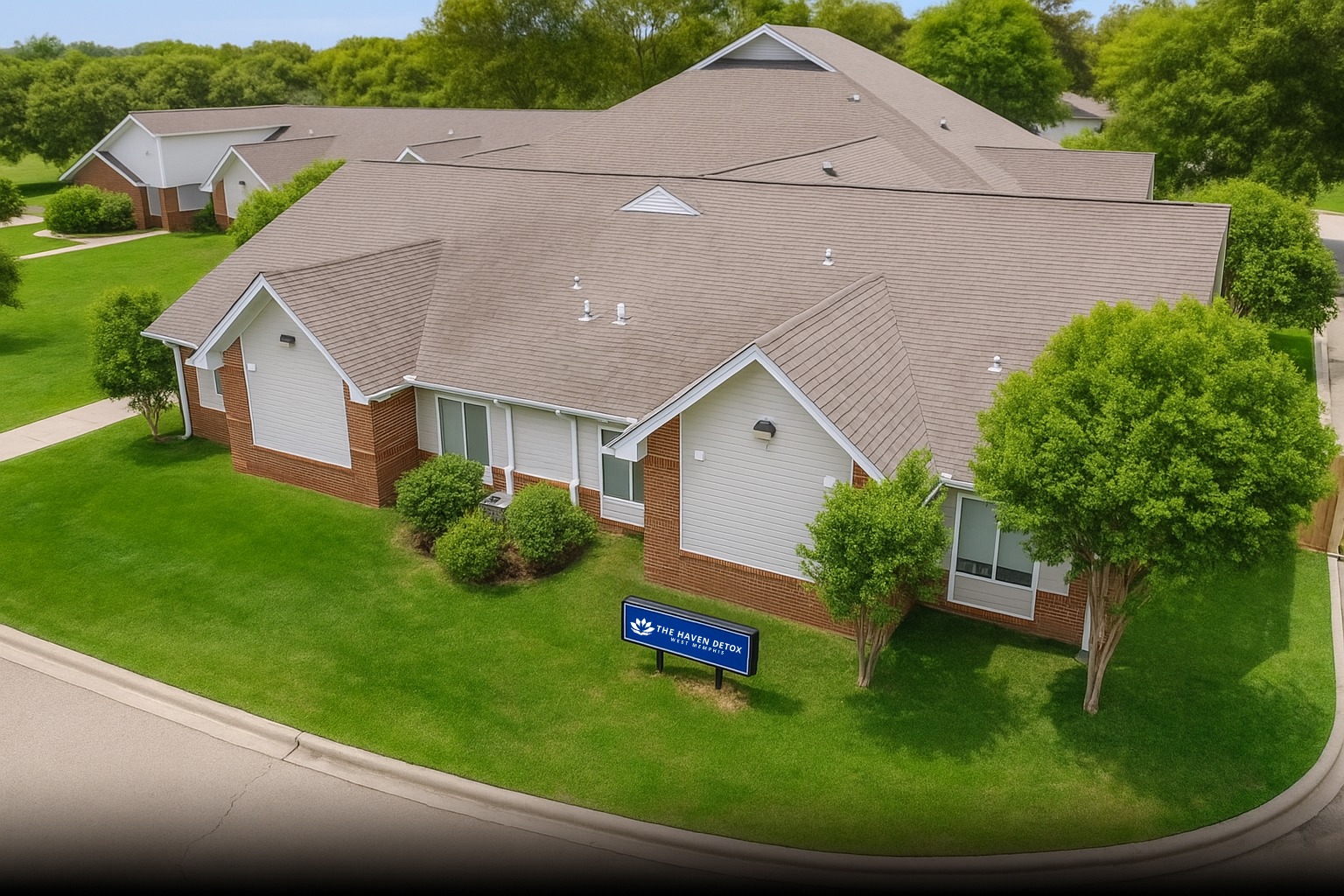 Aerial view of the facility with landscaped lawn and buildings.