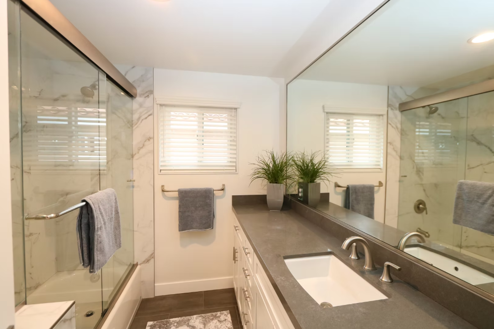 Bright bathroom with marble shower and large wall mirror