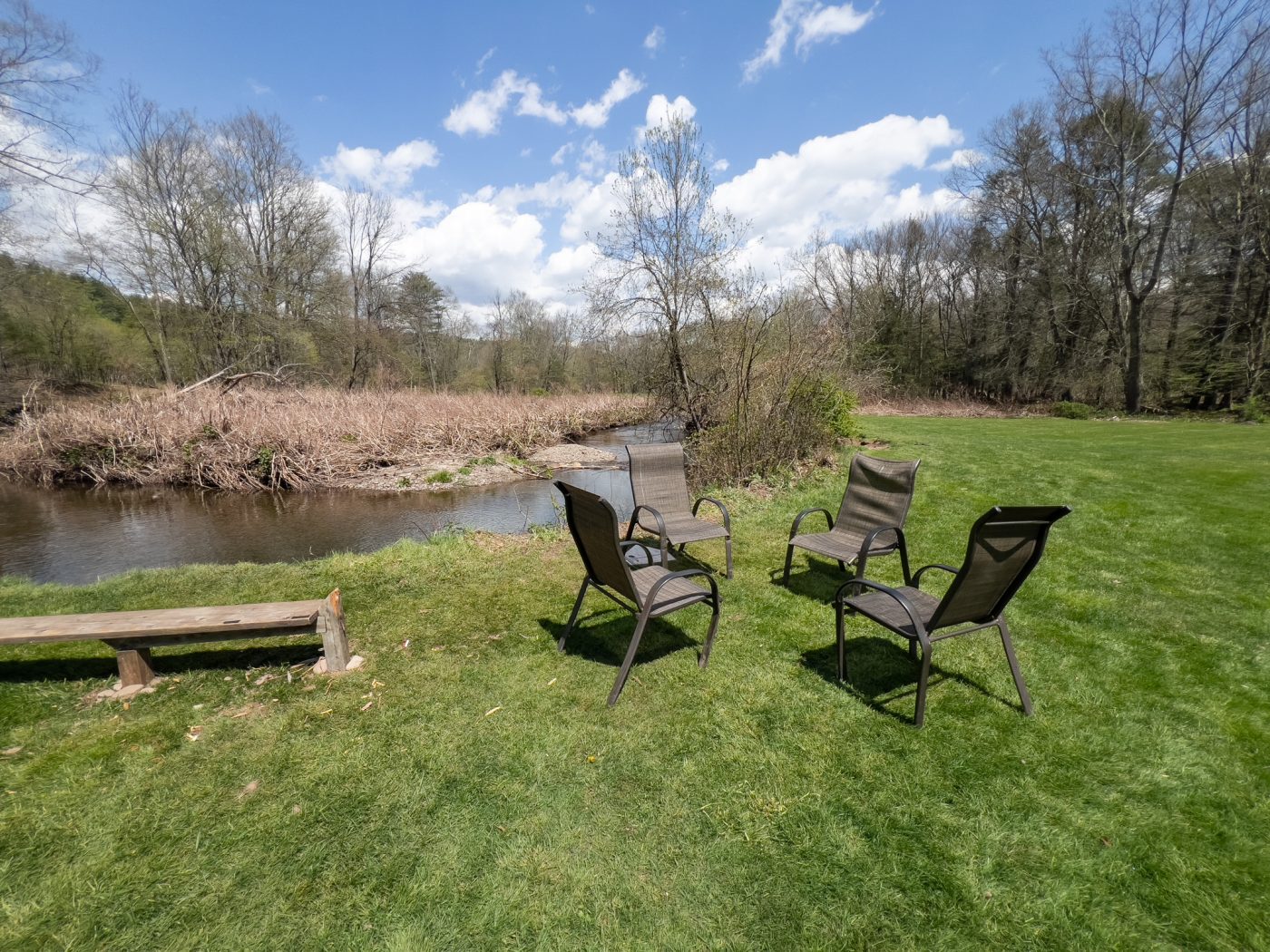 Lawn chairs by a creek on a sunny day