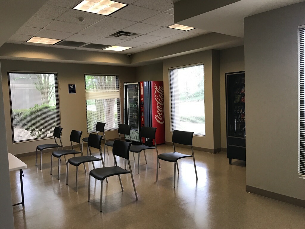 Break room with chairs, vending machines, and large windows.