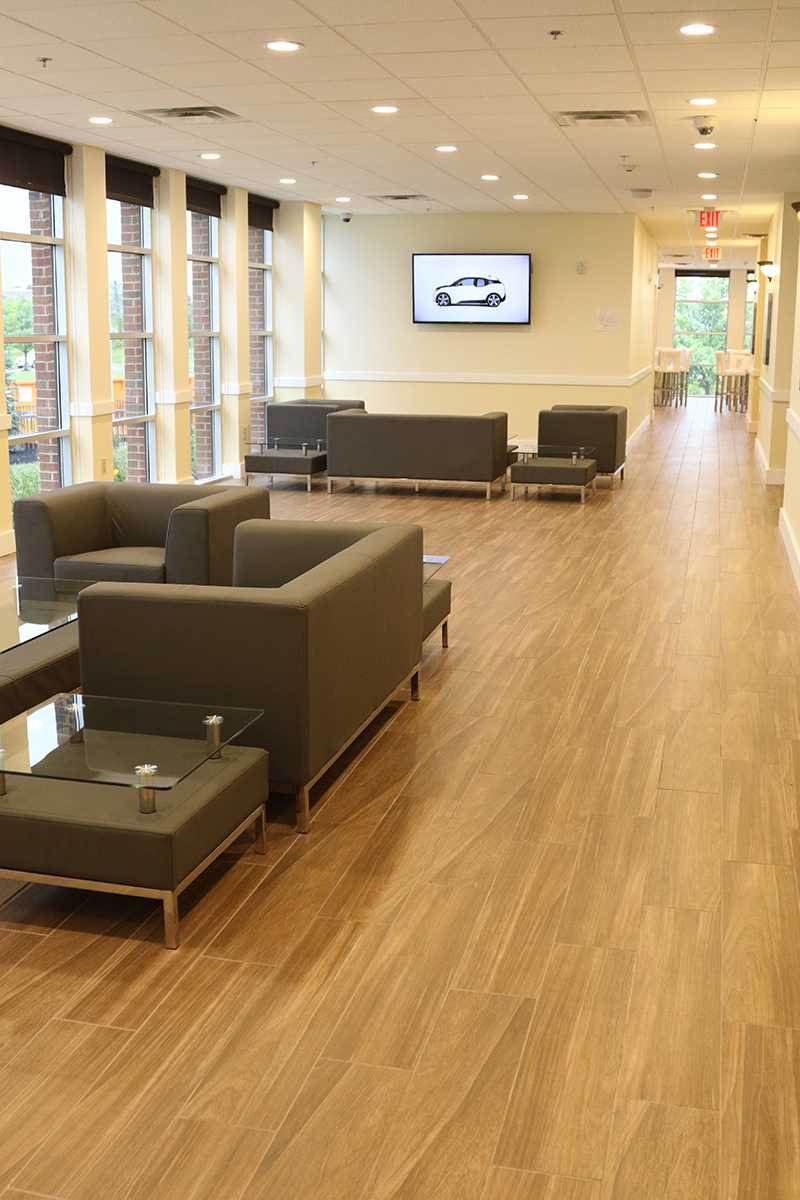 Sunlit waiting area with armchairs, TV, and large windows