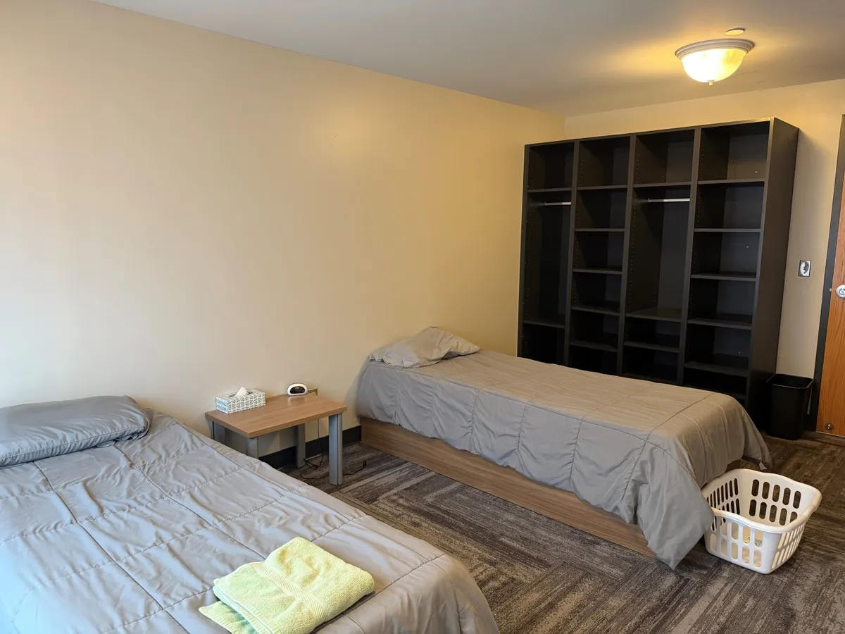 Shared bedroom with two single beds and open storage units