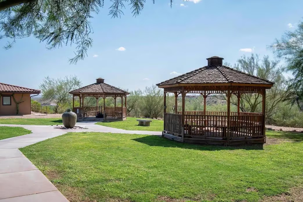Twin wooden gazebos on lawn with scenic desert views