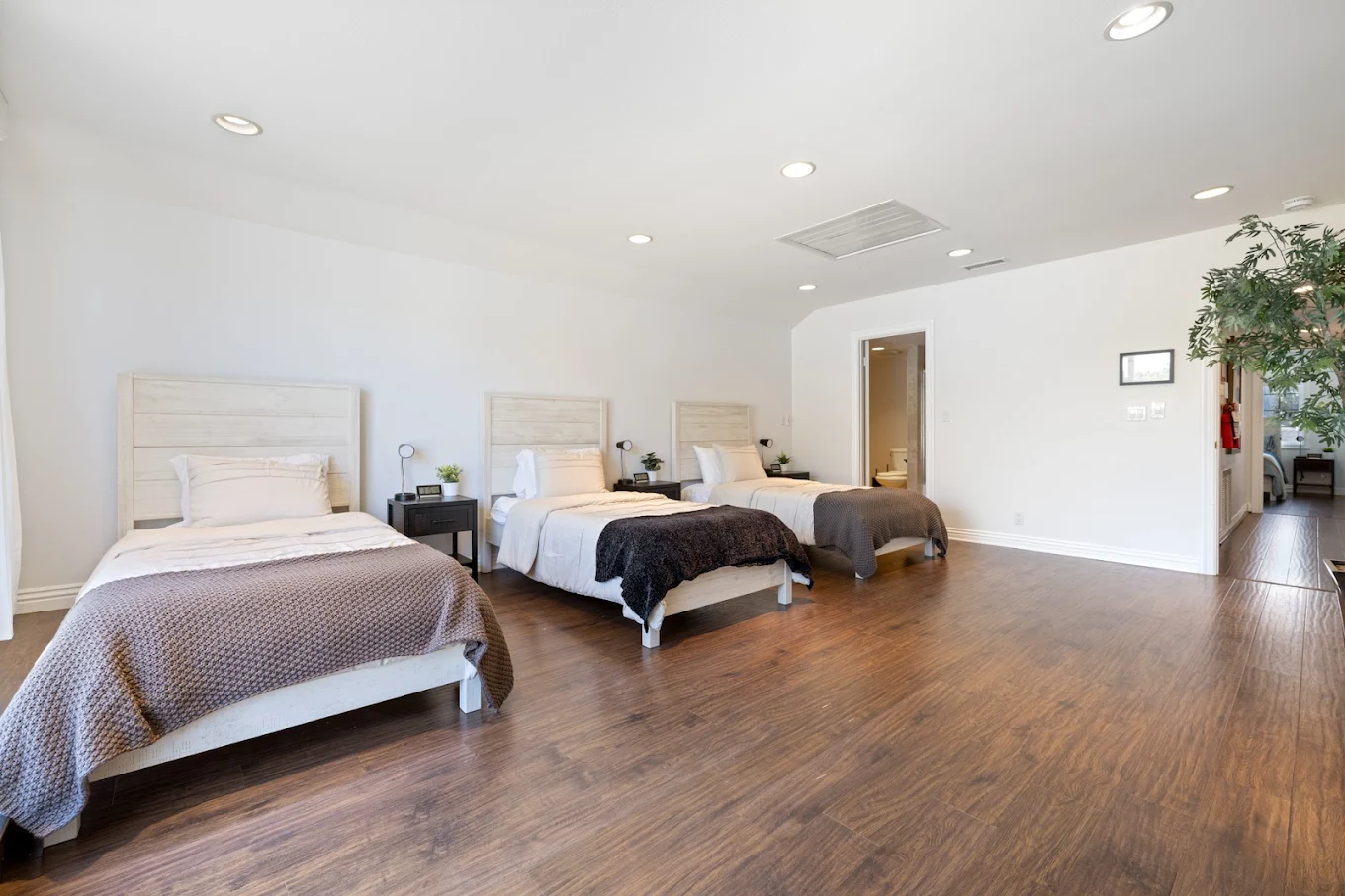 Room with three twin beds and wood flooring