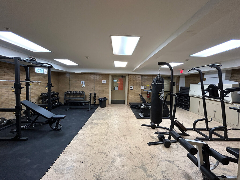 Fitness room with weight benches, dumbbells, machines, and a punching bag