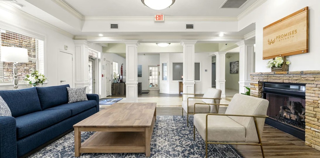Welcoming reception lobby with fireplace, comfortable seating, and Promises branding