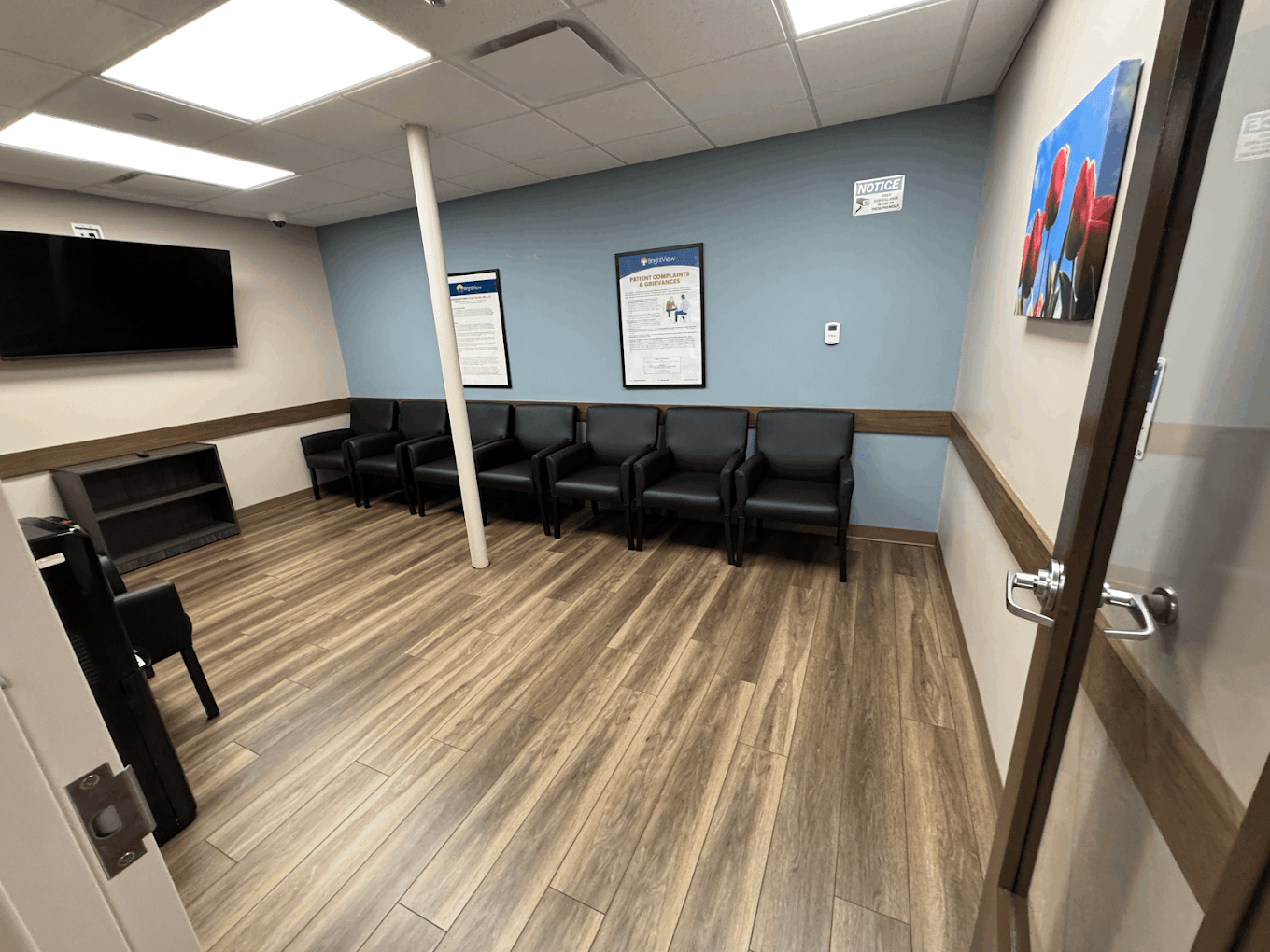 Waiting room with black chairs, wall art, and television