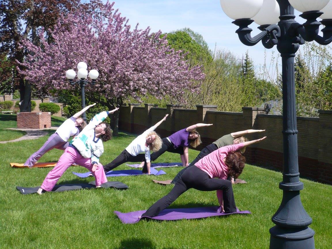 Women doing yoga in grass under pink-blossomed trees