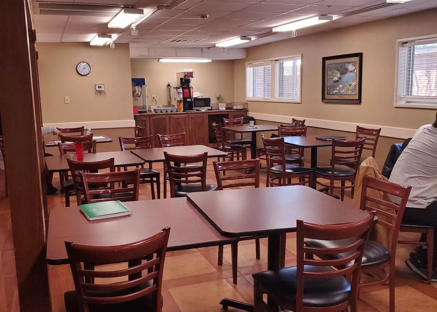 Cafeteria-style dining room with tables and kitchen area