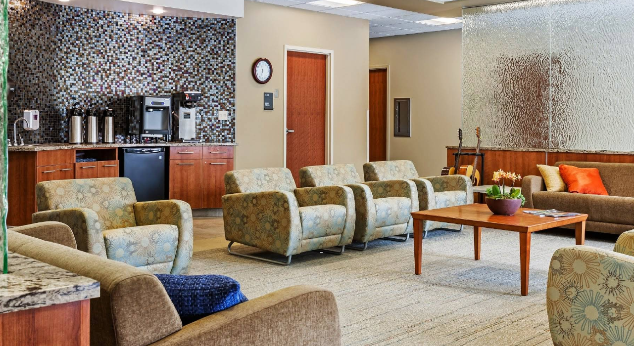 Comfortable waiting area with seating, coffee station, and tables