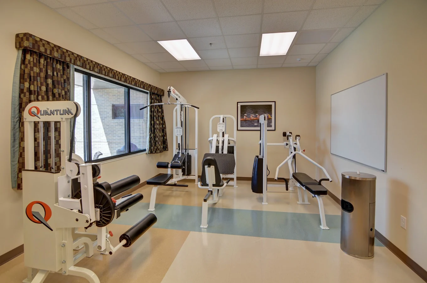 A well-lit gym with multiple exercise machines, including weight and resistance equipment, in a clean and organized room