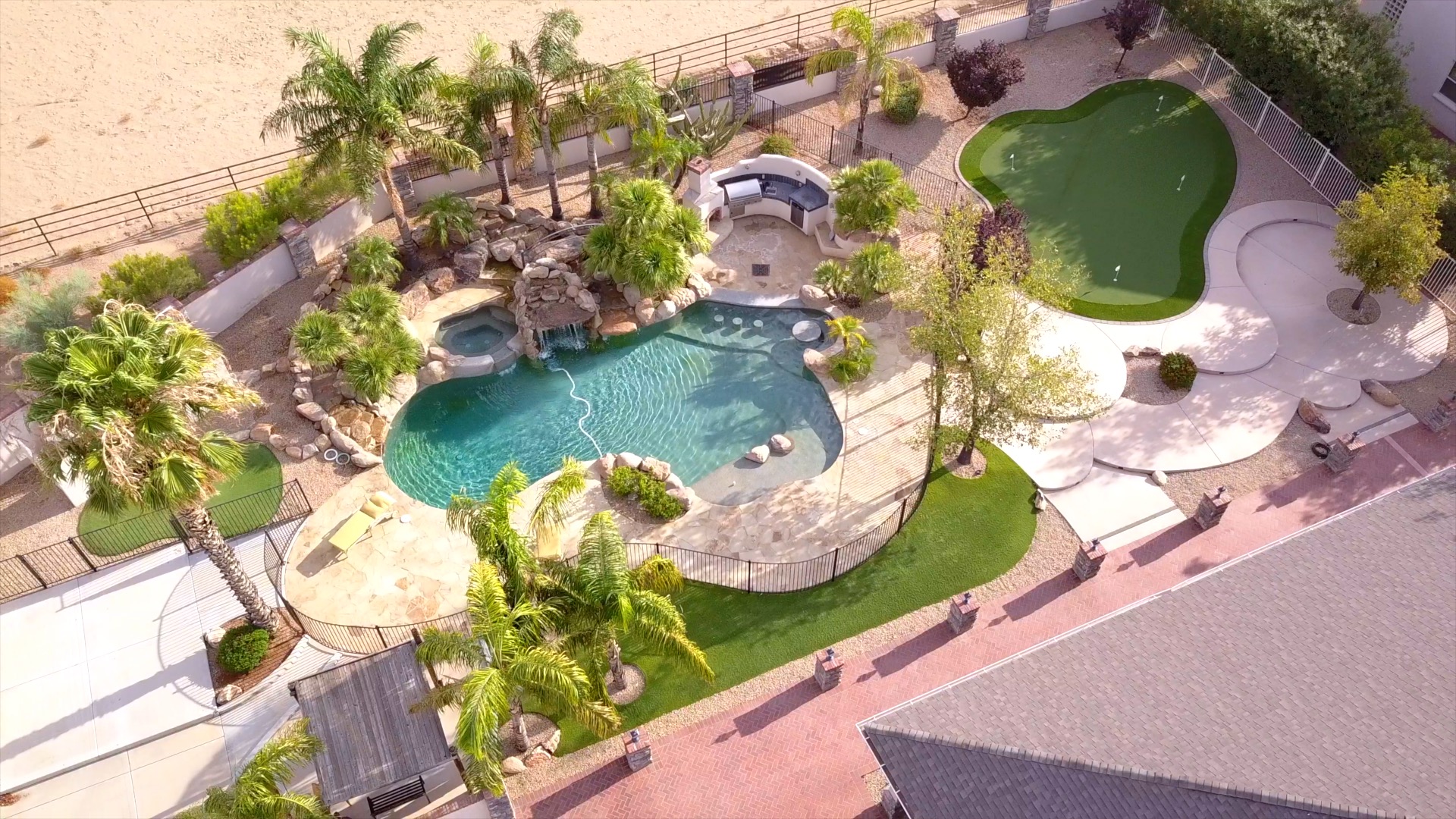 Aerial view of pool, waterfall, palms, and putting green