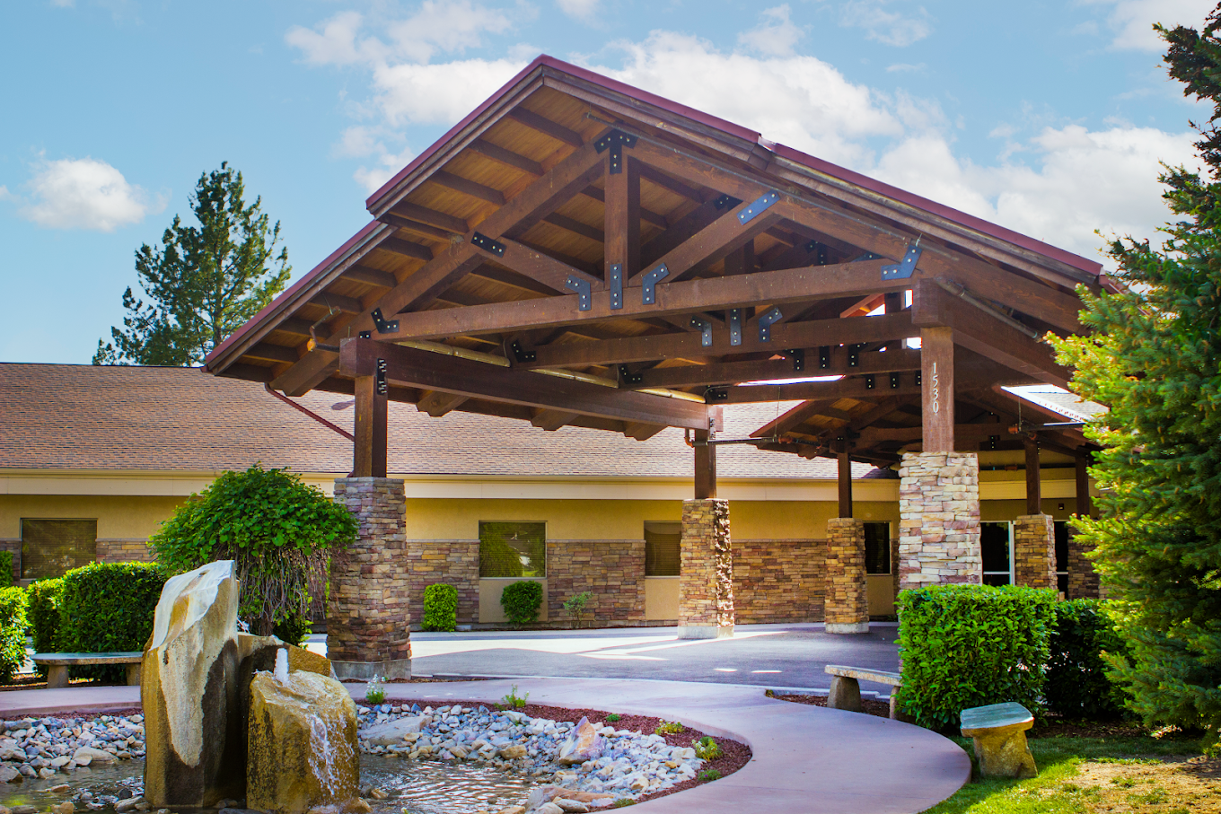 Exterior view of New Roads Behavioral Health with wooden portico, stone pillars, and landscaped fountain