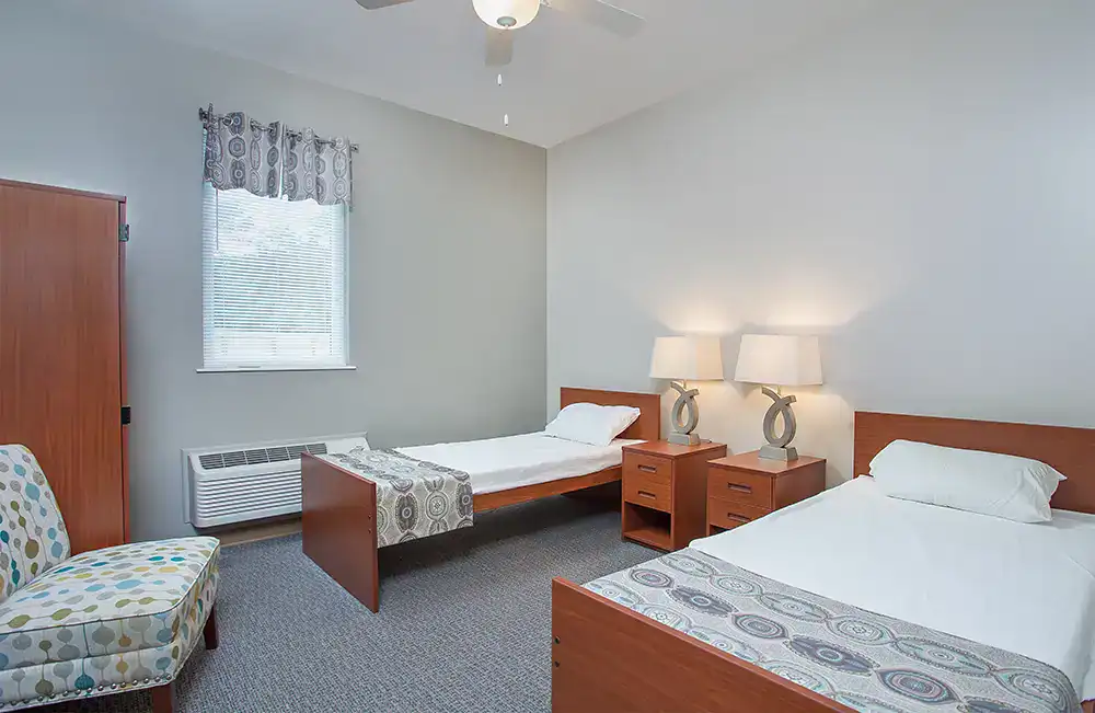 Two beds with nightstands, lamps, and natural lighting