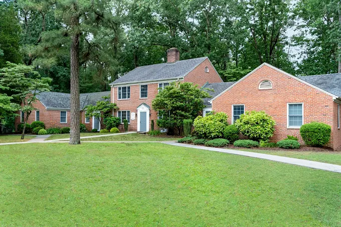 Red brick residential facility with green lawn and trees