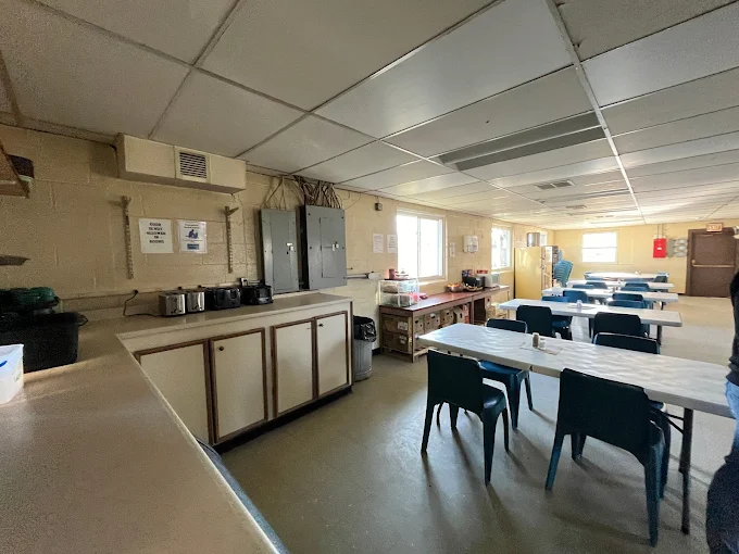 Communal dining room with long tables and serving area