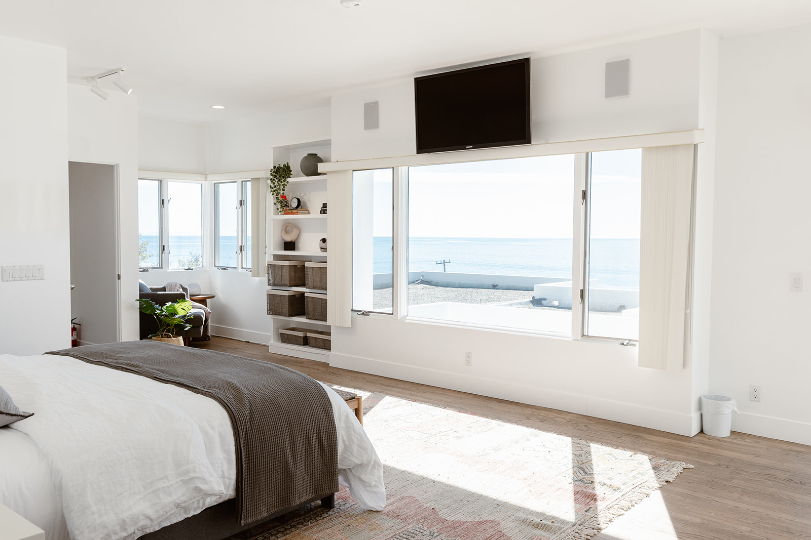  Bright bedroom with ocean views, modern decor, and built-in shelving.