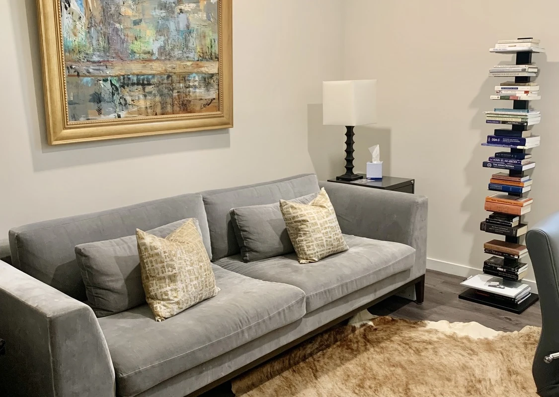 Gray couch with pillows beneath abstract framed artwork