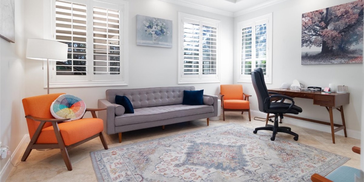 Therapy lounge with gray sofa, orange chairs, and wooden desk