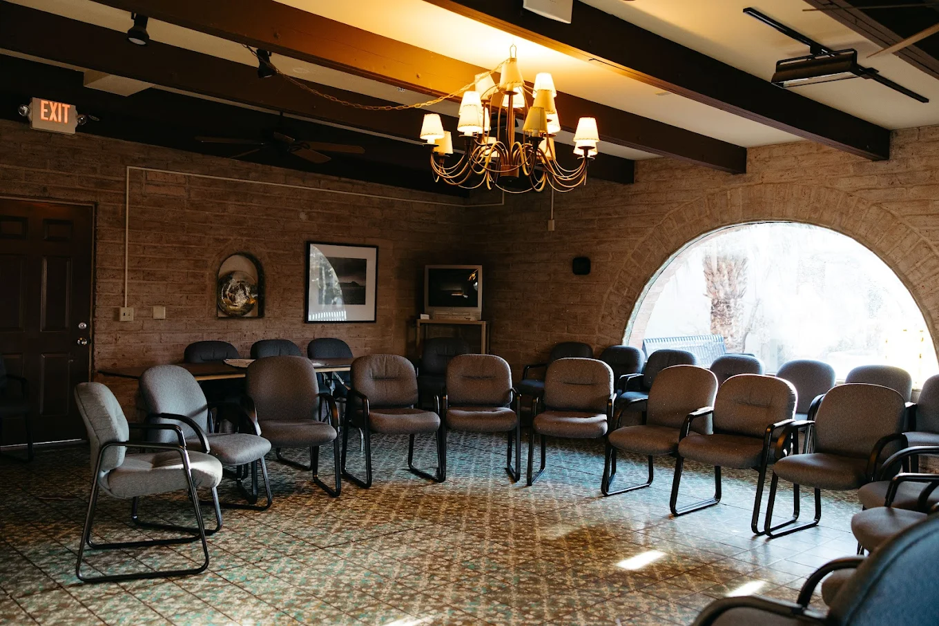Circle of chairs in rustic room with arched window