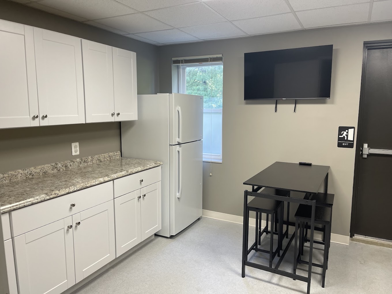A kitchen area with cabinets, a fridge, and a small dining table.