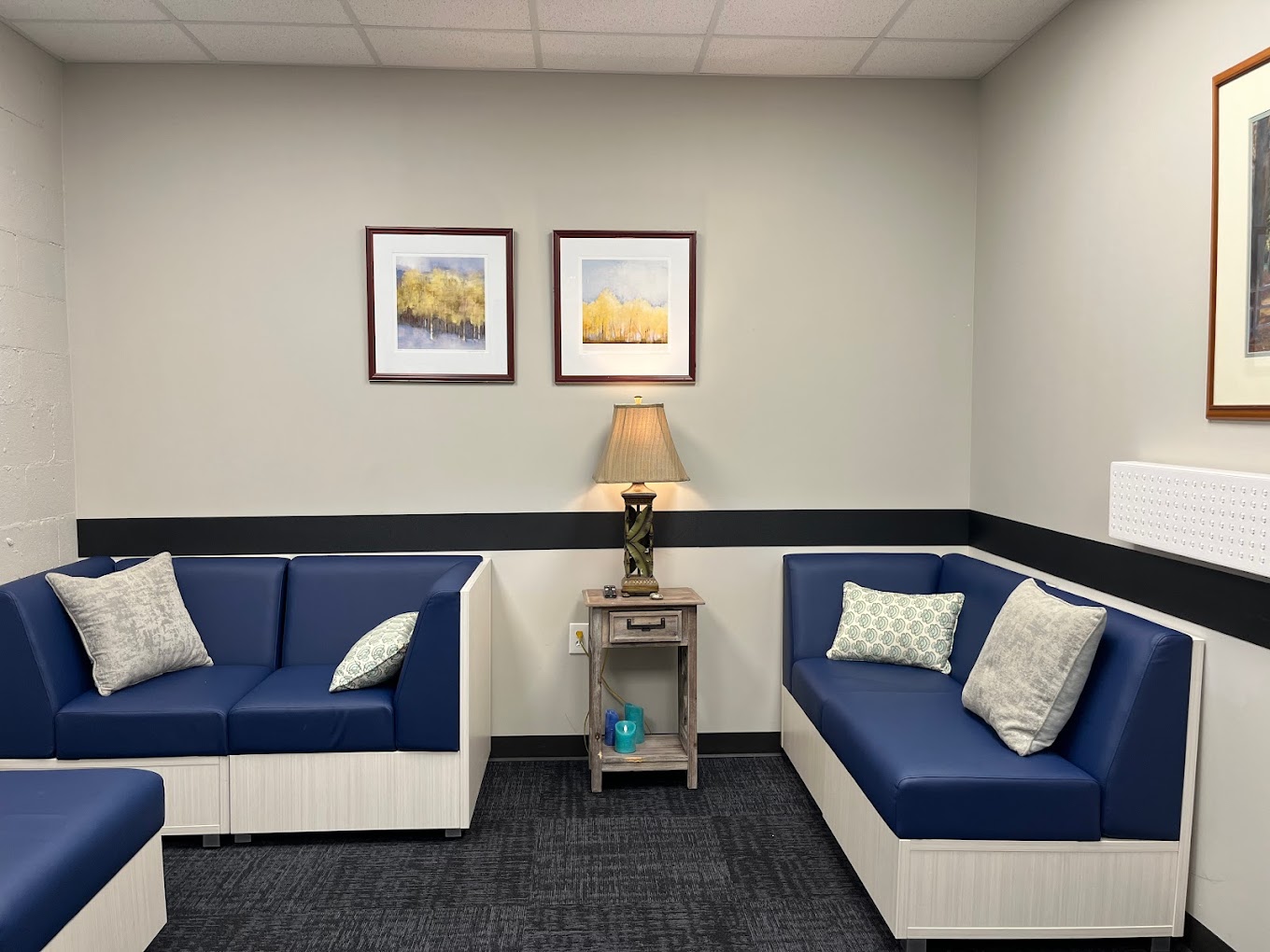 A seating area with blue cushioned sofas and framed artwork.