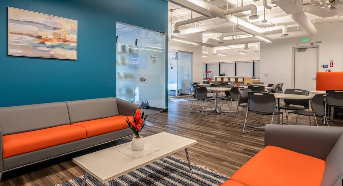 Bright lounge with couches and dining area in rehab facility