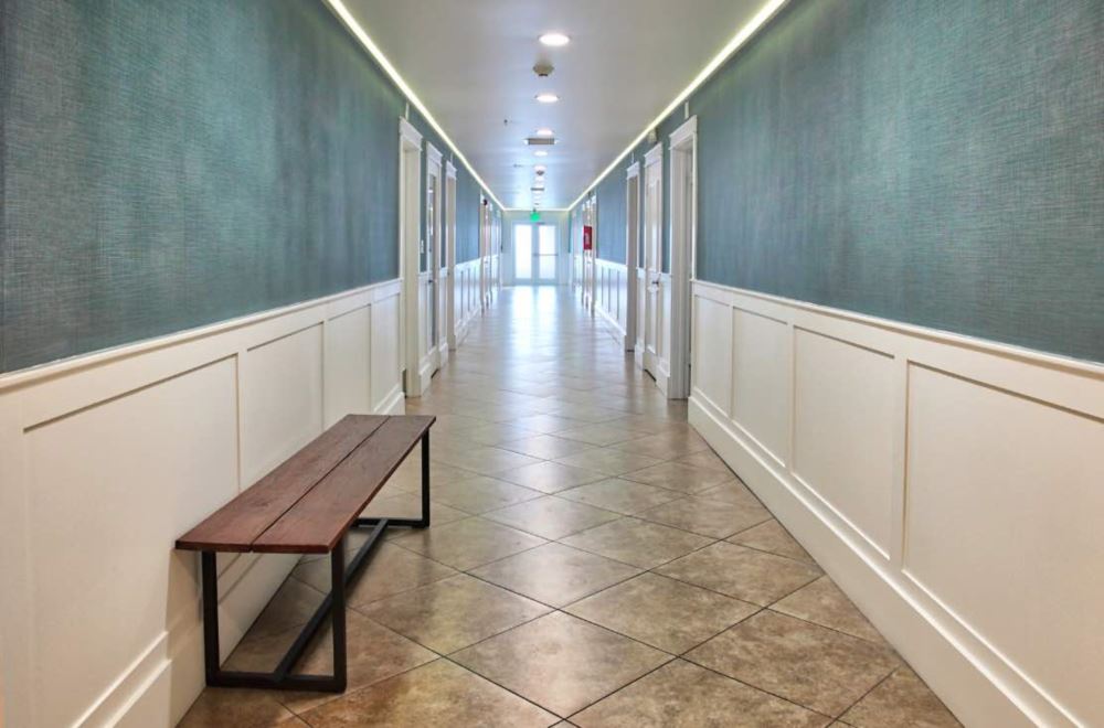 Long hallway with bench and white paneling on both walls