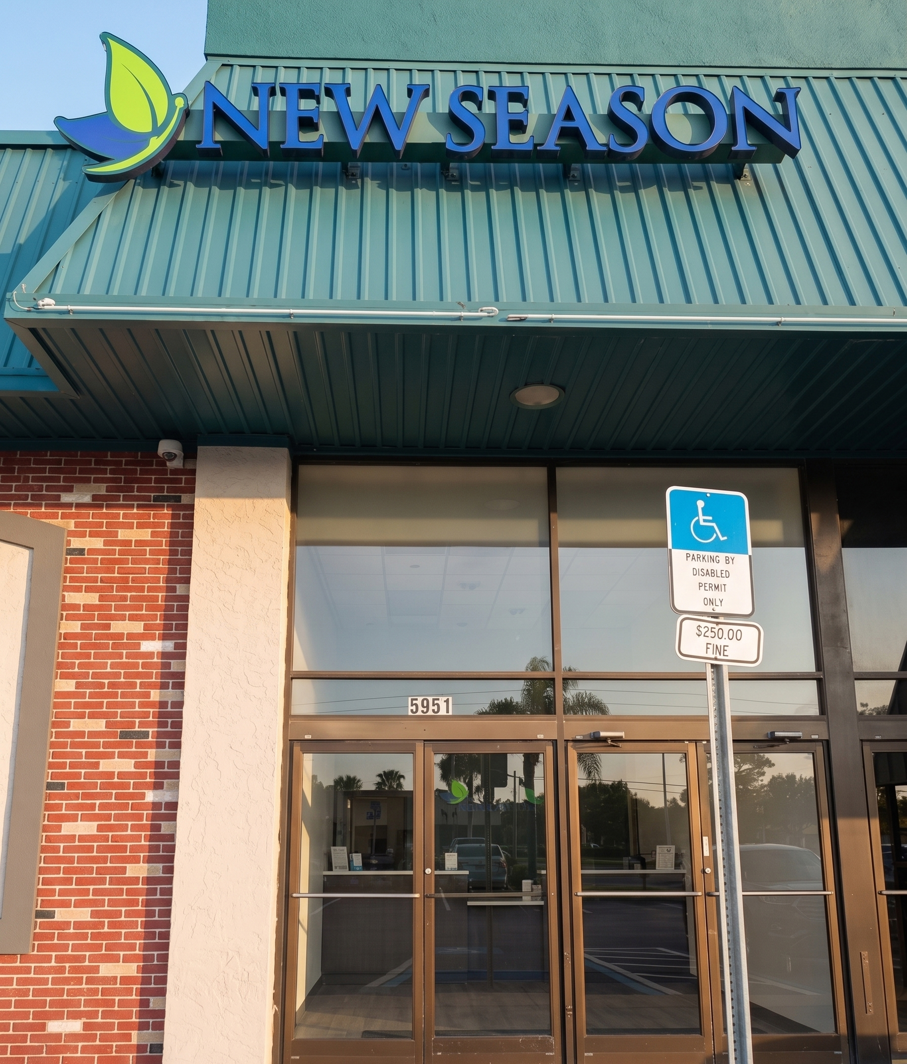 New Season entrance with glass doors and accessible parking sign