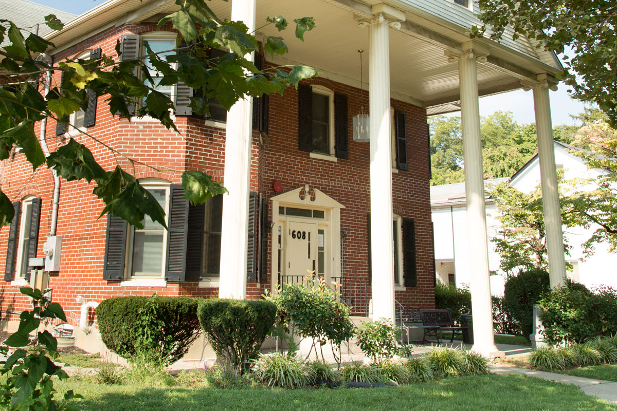 Brick house with white columns and black shutters on a sunny day