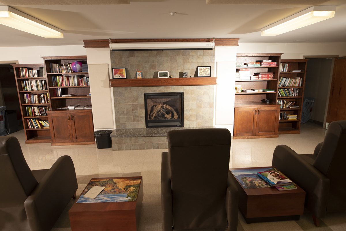 Library lounge with fireplace, bookshelves, and comfortable chairs