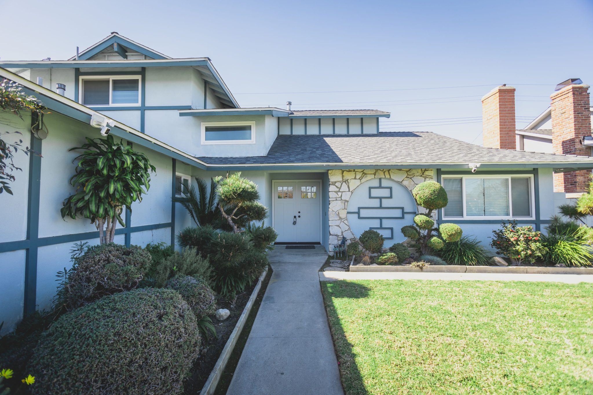 The exterior of a blue and white rehab facility with a landscaped front yard.