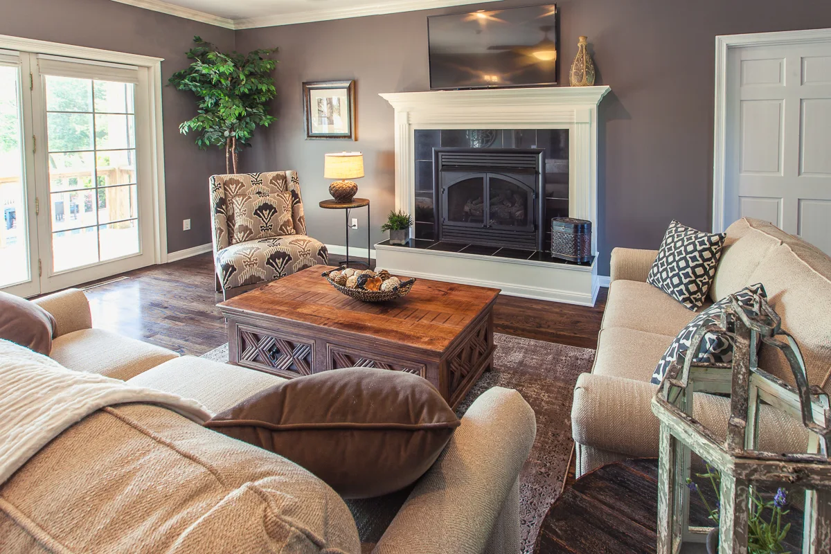 Comfortable living room with sofas, a wood coffee table, and a white-trimmed fireplace beneath a mounted TV
