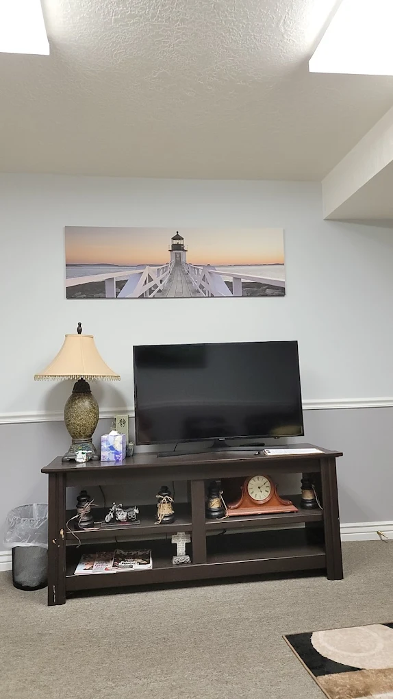 TV on stand in carpeted lounge with lighthouse wall art