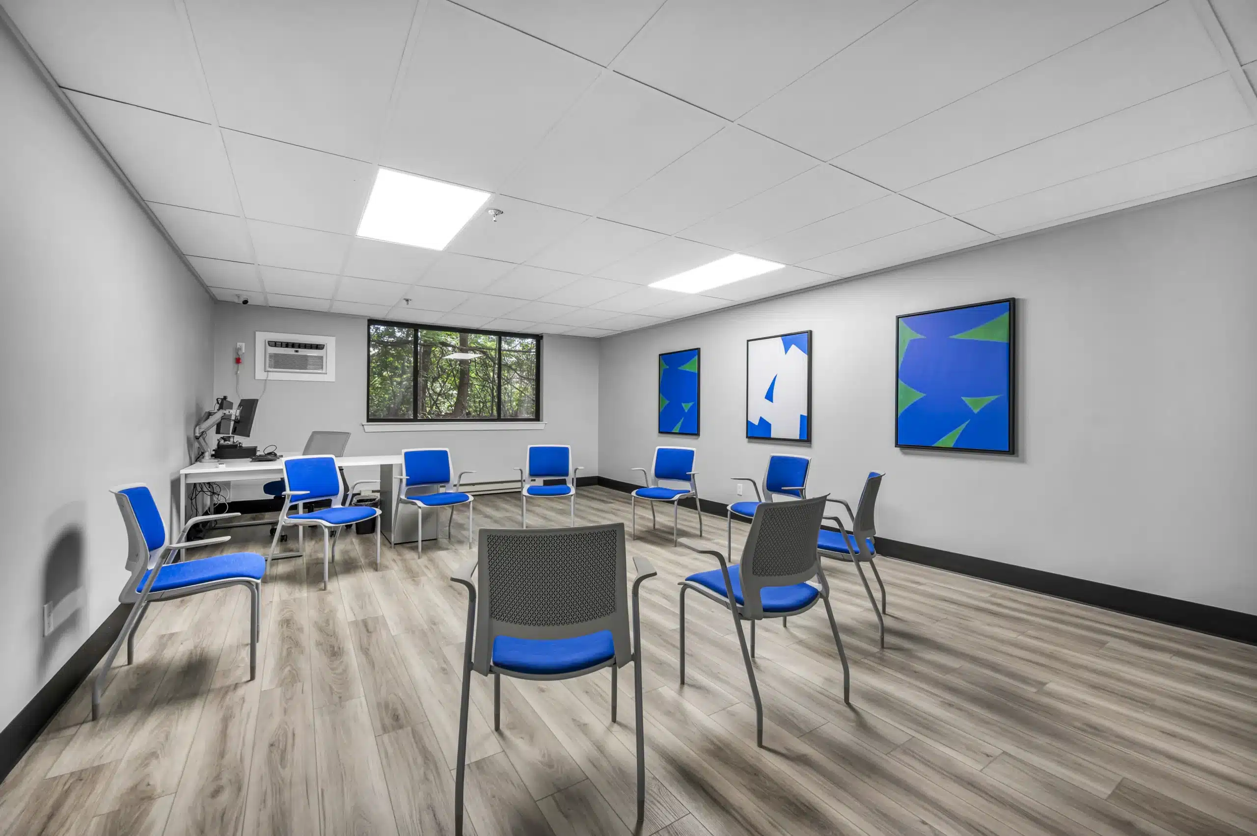 Group therapy room with blue chairs arranged in a circle and modern wall art at Boca Recovery Center Massachusetts
