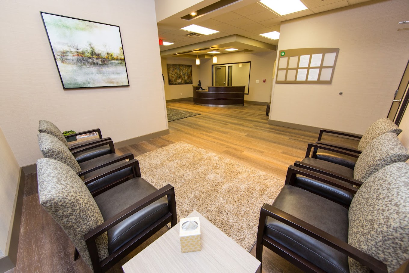Reception area with a circular front desk and seating area with black chairs