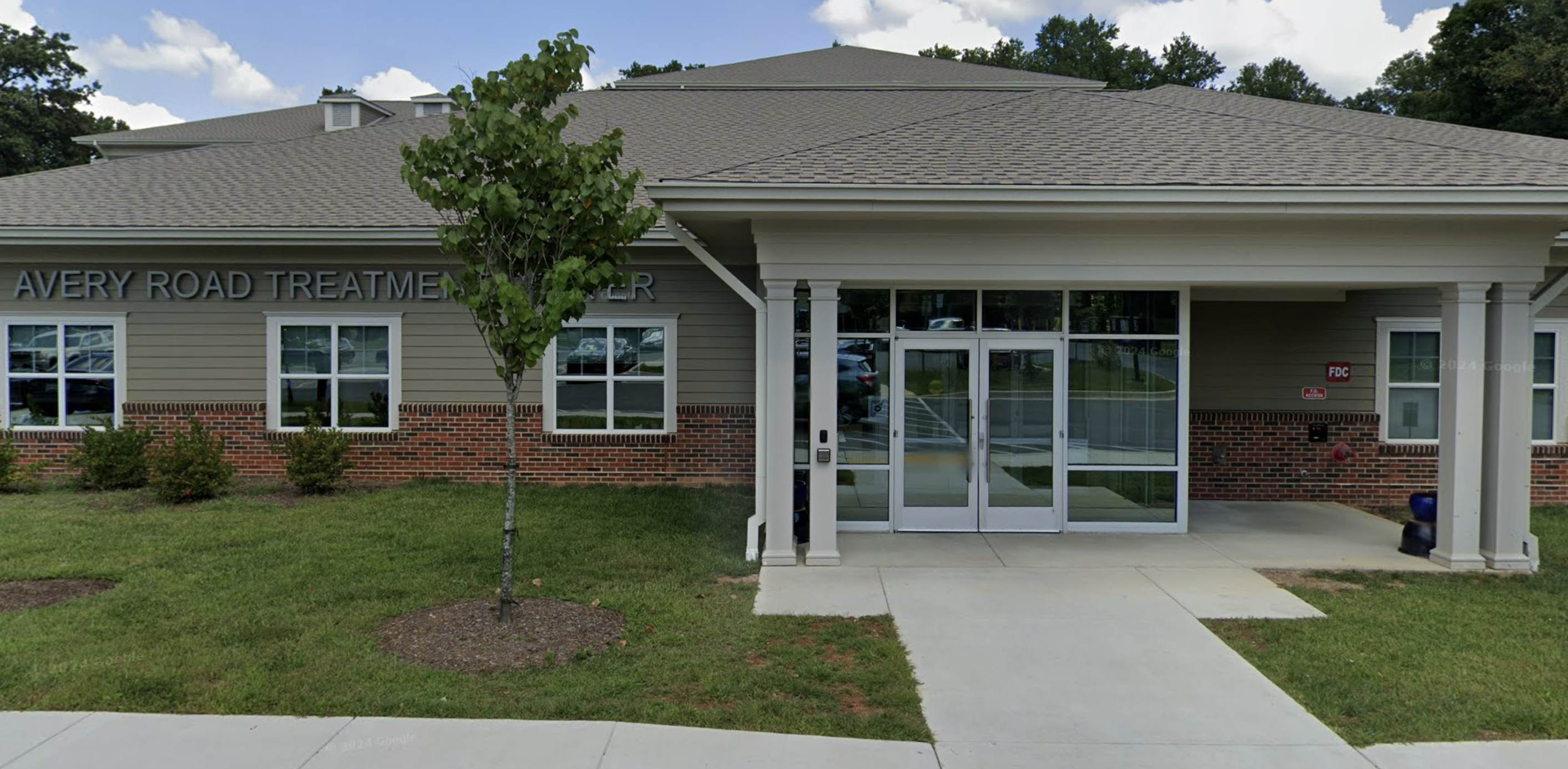 Covered front entrance with glass doors and landscaped walkway